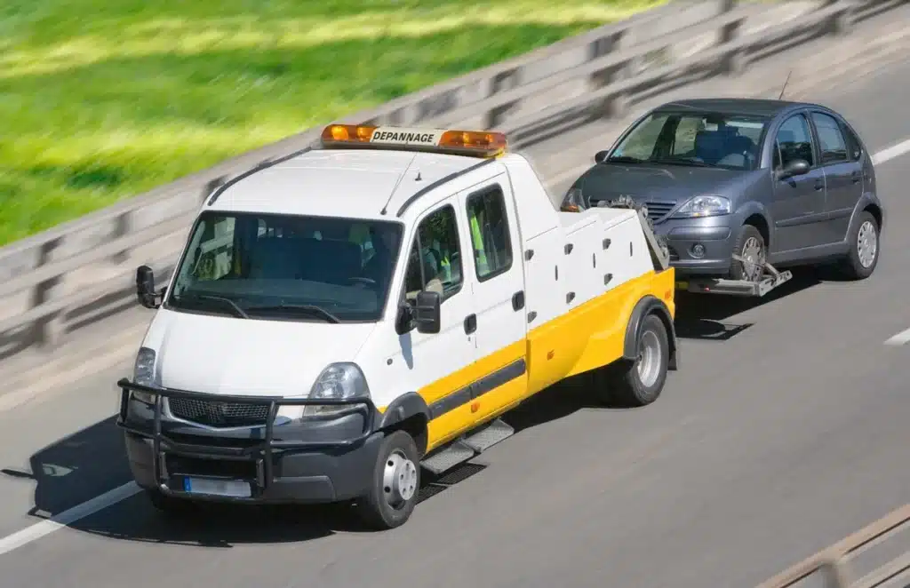 camion de dépannage transportant une voiture sur une route rapide, illustrant un service de dépannage auto rapide et sécurisé